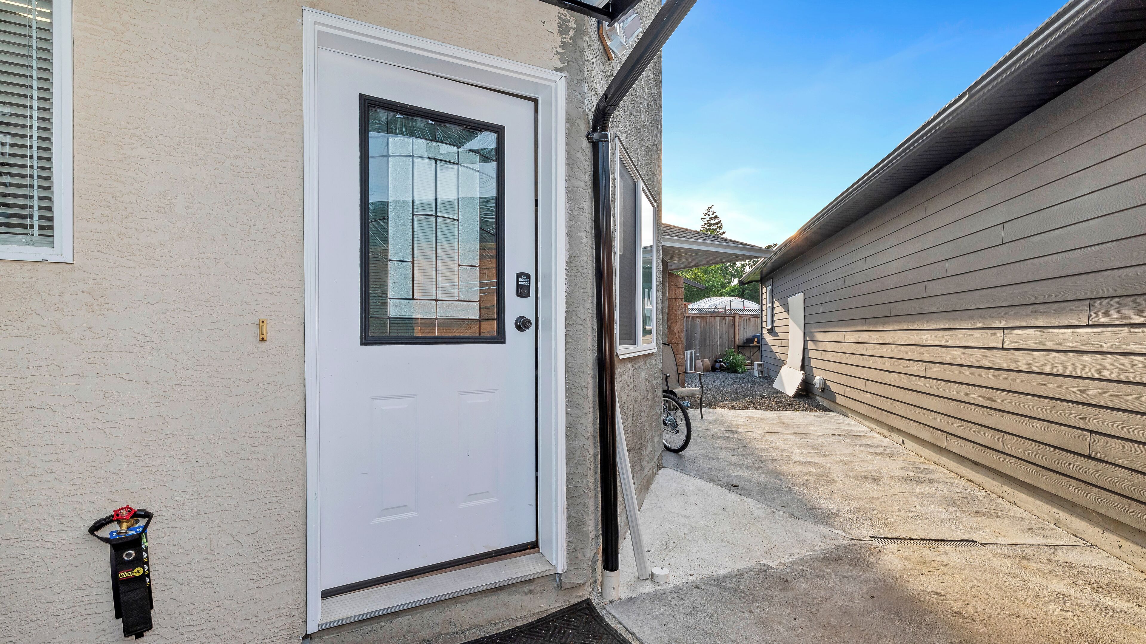 A residential exterior with a white door, a garage door, and a wooden fence.