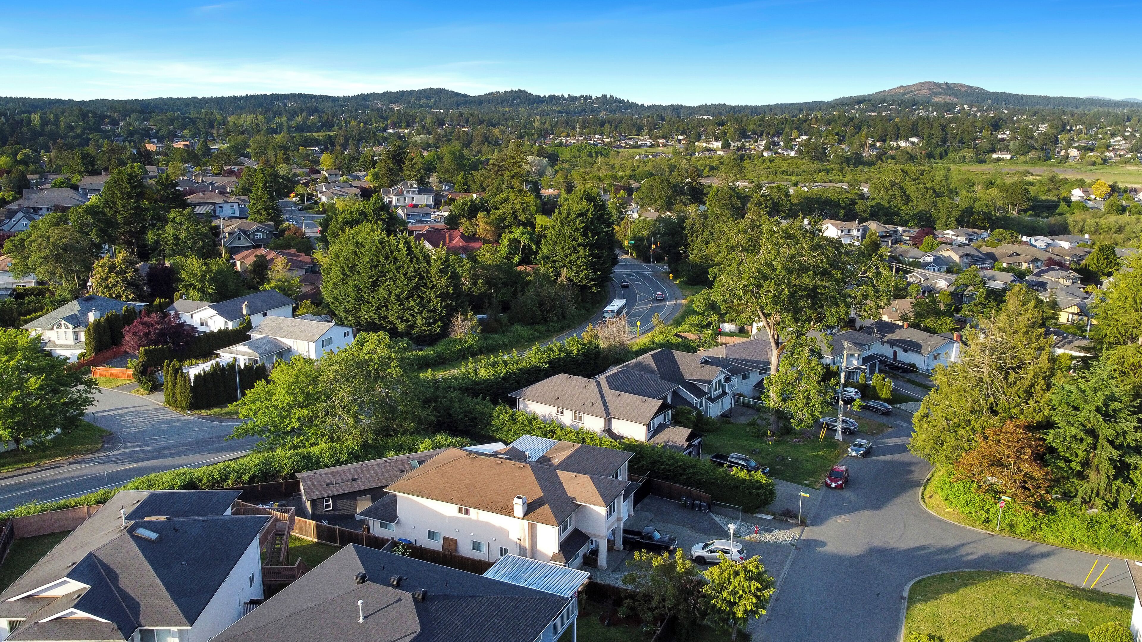 A residential area with houses, roads, and a hilly landscape in the background.