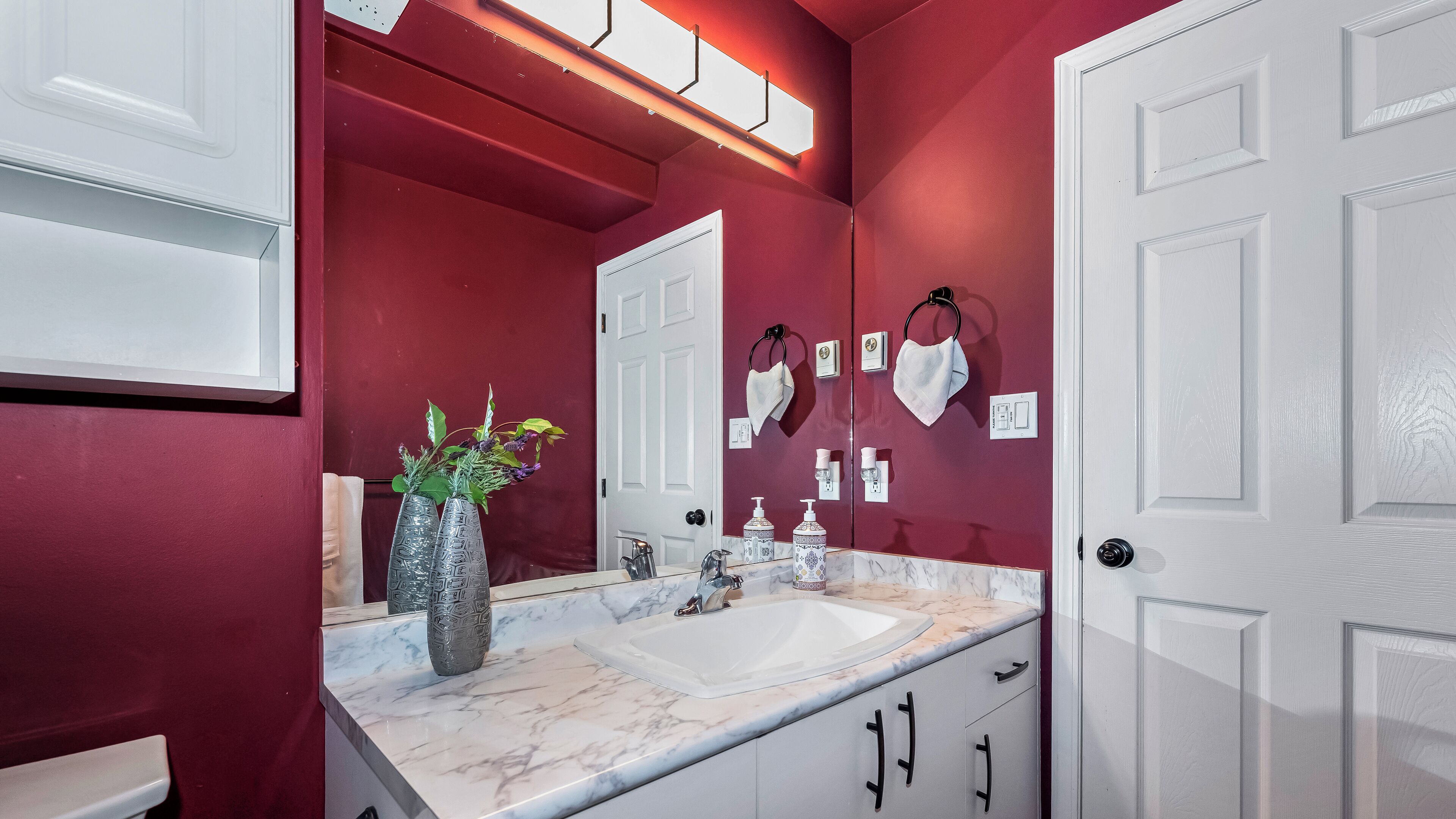 A bathroom with a white sink, marble countertop, and a mirror with a towel rack.