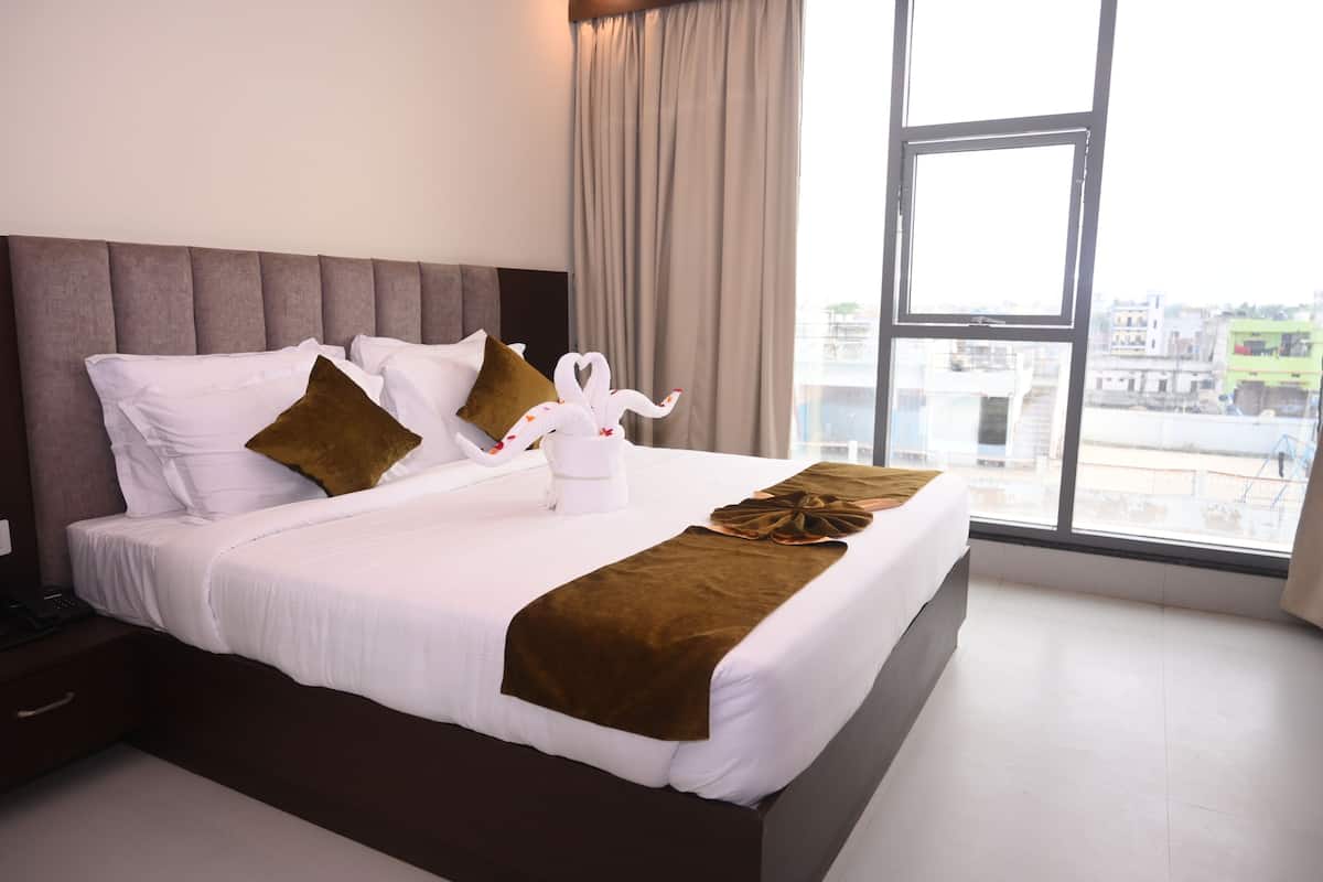 Ett hotellrum med en stor säng, utsikt över staden genom ett fönster och en brun pläd.