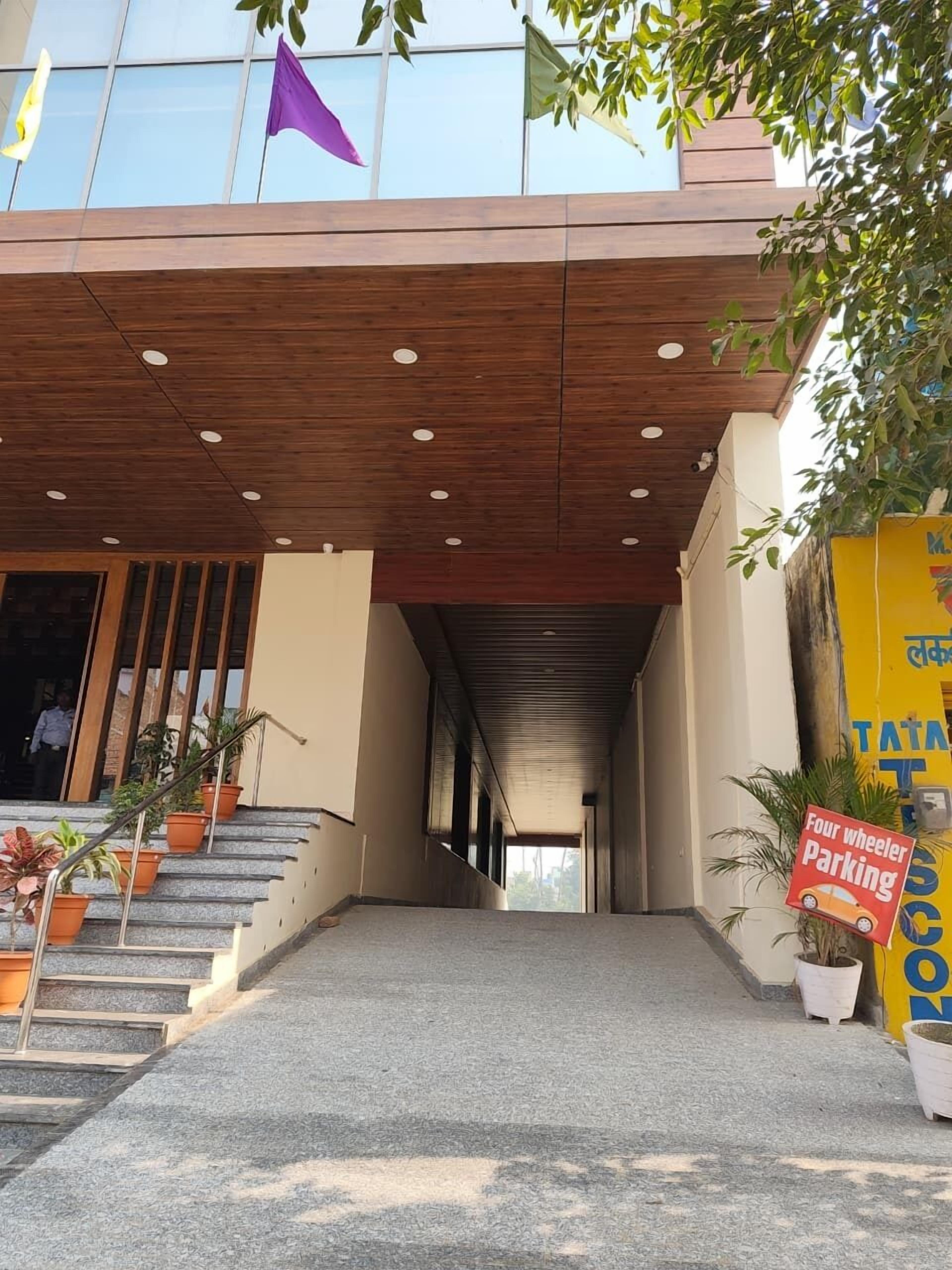 A building entrance with a wooden overhang, a staircase with potted plants, and a sign indicating four-wheeler parking.