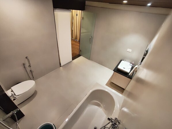 A modern bathroom with a toilet, bathtub, and sink. - HOTEL MAHIKA (Siwan)
