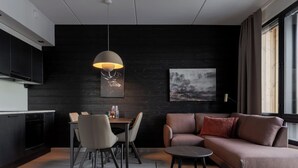A modern living space with a dining area, a sofa, and a pendant light. - Le Chalet Lingonberry D6 by Aavalevi (Levi)