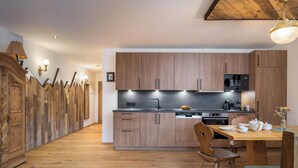 A modern kitchen with wooden cabinets, a dining area with a table and chairs, and a decorative wall with a unique design.