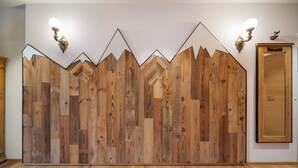 A room with a wooden wall panel design, a wooden door, and two wall-mounted light fixtures.