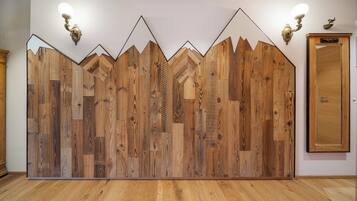 Une pièce dont un mur est recouvert de panneaux en bois, avec une porte en bois et deux appliques murales.