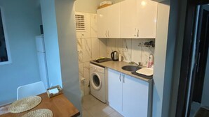 A compact kitchen with a washing machine, a sink, and cabinets. - SOYDAN WORLD TRAVEL APART HOTEL (Antalya)