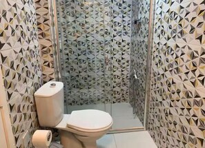 A bathroom with a geometric patterned wall, a toilet, and a shower area. - SOYDAN WORLD TRAVEL APART HOTEL (Antalya)