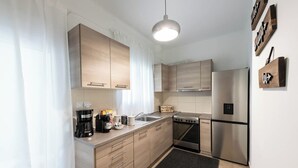 Een moderne keuken met lichte houten kastjes, roestvrijstalen apparatuur, een koffiezetapparaat en een broodrooster.