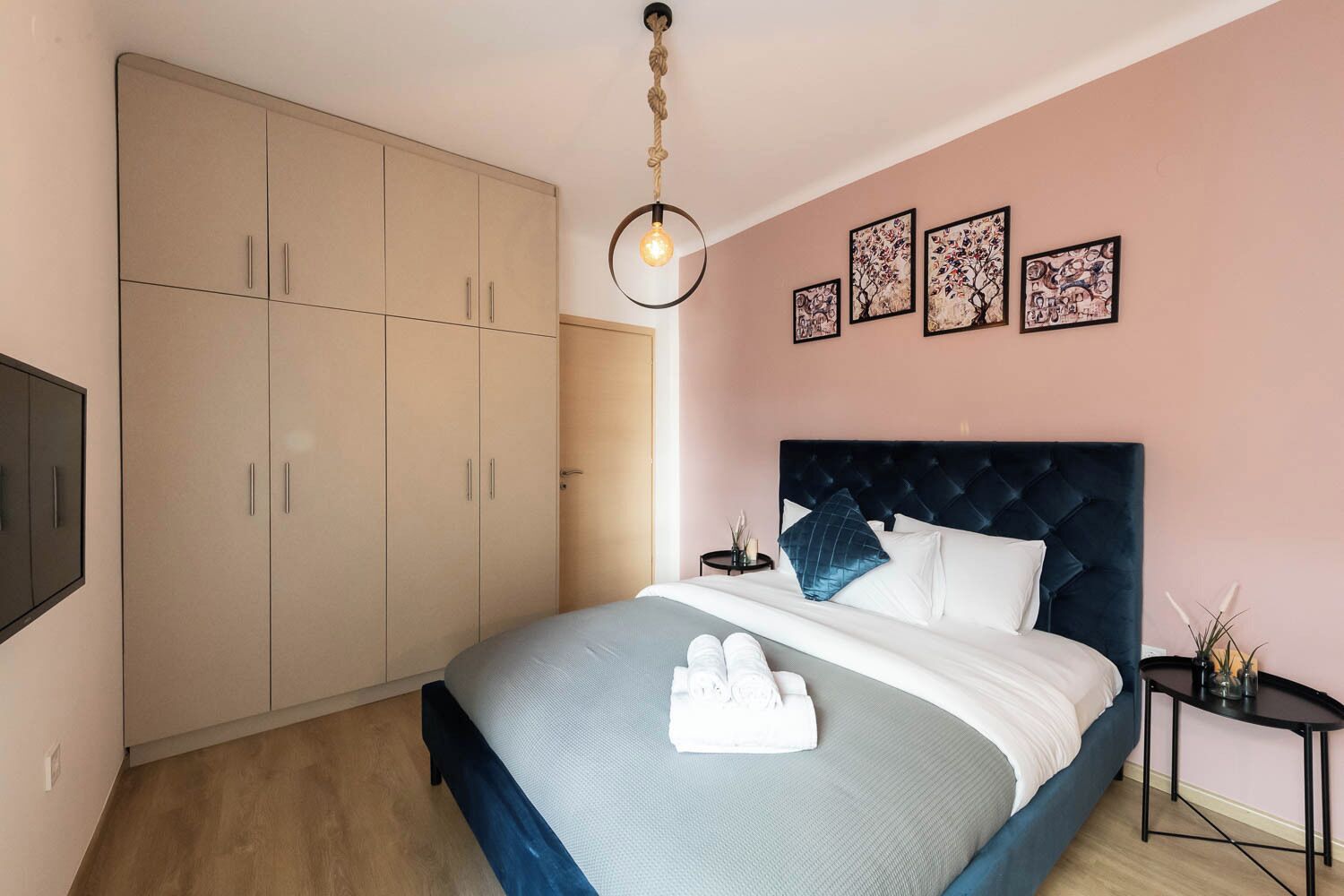 A bedroom with a bed, a wardrobe, a bedside table, and wall art.