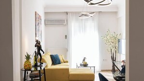 Een moderne woonkamer met een gele bank, een klein tafeltje met een ananas en een bijzondere lamp.