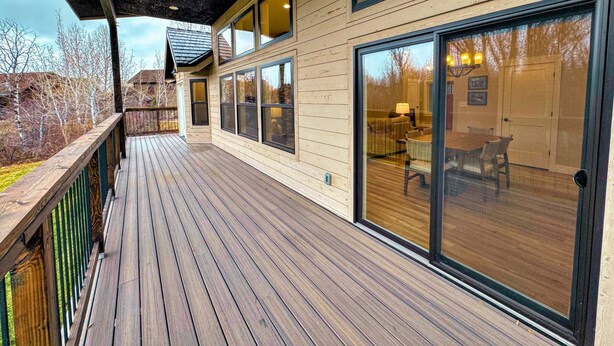 A wooden deck with a glass door leading to a dining area. - Modern Mountain Family Home on Ski Hill Road — Pet Friendly + A/C (Driggs)