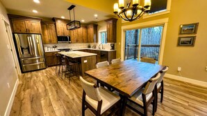 A modern kitchen with wooden cabinets, stainless steel appliances, and a large island with bar stools. - Modern Mountain Family Home on Ski Hill Road — Pet Friendly + A/C (Driggs)