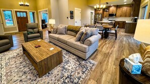 A spacious living room with a large sofa, a coffee table, and a dining area with a table and chairs. - Modern Mountain Family Home on Ski Hill Road — Pet Friendly + A/C (Driggs)