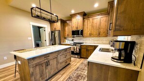 A modern kitchen with wooden cabinets, stainless steel appliances, and a large island. - Modern Mountain Family Home on Ski Hill Road — Pet Friendly + A/C (Driggs)