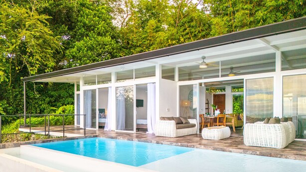 Une maison moderne dotée d’une piscine, d’un espace salon extérieur et d’un coin repas.