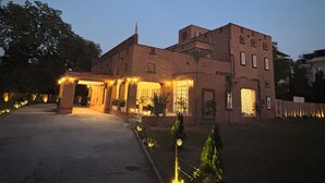 A brick building with a covered entrance and a garden area. - Surya Niwas Boutique Hotel & Garden (Jodhpur)