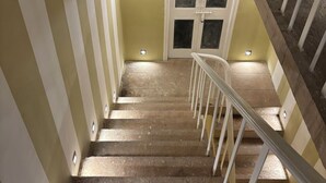 A staircase with a handrail, leading to a landing with a door and windows. - Surya Niwas Boutique Hotel & Garden (Jodhpur)