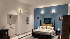 A bedroom with a bed, bedside tables, a wardrobe, a mirror, and a window. - Surya Niwas Boutique Hotel & Garden (Jodhpur)