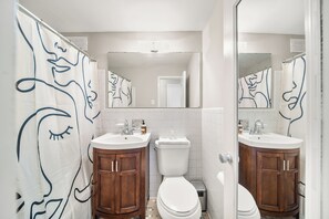 Een badkamer met twee wastafels, een toilet en houten kastjes.
