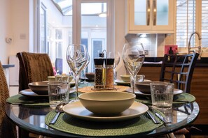 Une table à manger dressée avec de la vaisselle transparente, des bols et des couverts, et un salier et un poivrier au centre.