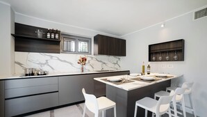 Una cocina moderna con encimera de mármol, armarios de madera oscura y una isla central con taburetes de bar.