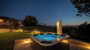 Un jacuzzi en un área exterior bien iluminada con vista al cielo y montañas distantes.