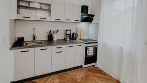 Una cucina moderna con mobili bianchi, un piano cottura nero e un pavimento in legno a spina di pesce.