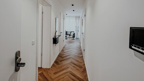 Un corridoio con pareti bianche, pavimento in legno e illuminazione a incasso.