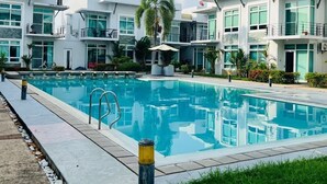 A modern hotel with a central swimming pool, surrounded by well-maintained greenery and a clear sky. - Cozy 1 bedroom condo inside Subic Bay Freeport Zone with complete amenities. (Subic Bay Freeport Zone)