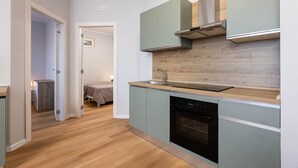 A modern kitchen with light green cabinets, a wooden countertop, and a built-in oven. - Sea View Apartment (Margherita di Savoia)