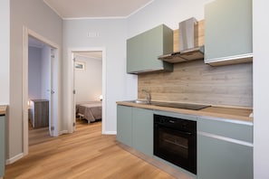 Una cocina moderna con armarios verde claro, una encimera de madera y un horno empotrado.