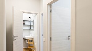 Ein Flur mit Holzdielen, weißen Wänden und zwei geschlossenen Türen.