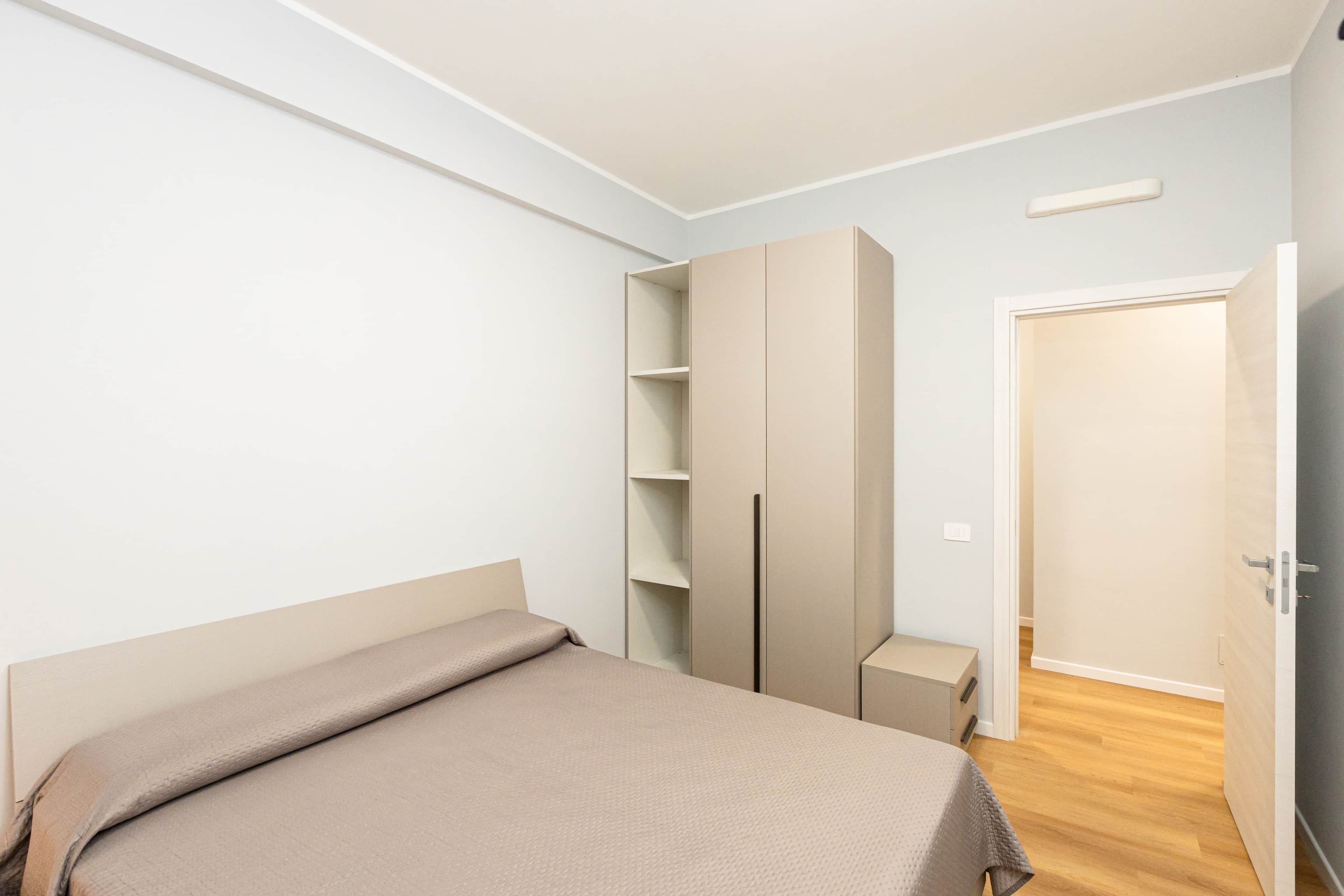 Un dormitorio con una cama, un armario y una puerta.