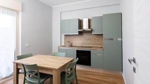 Eine kleine Küche mit Holztisch und -stühlen, einem eingebauten Ofen und einem Spülbecken.