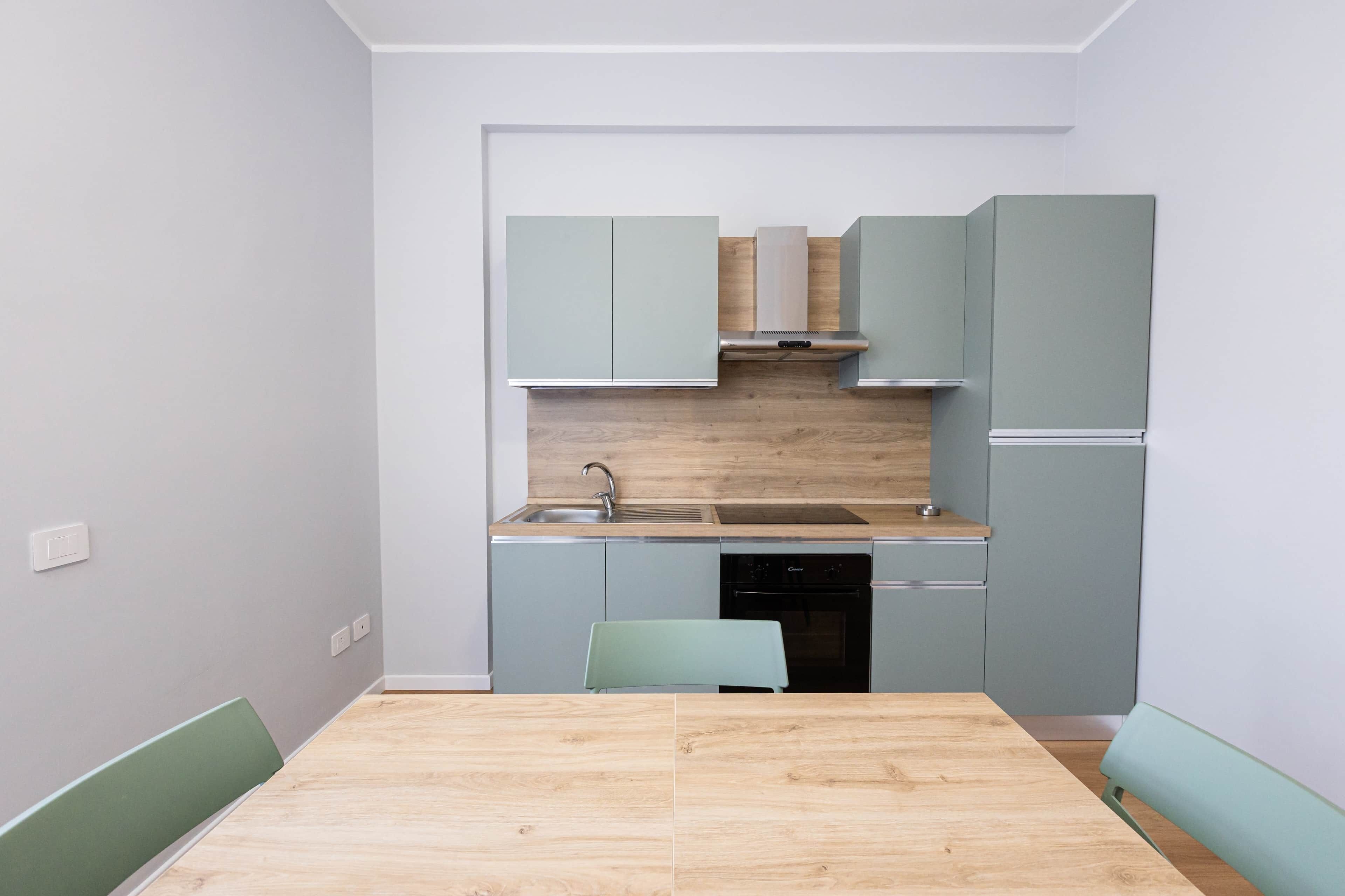 Une cuisine compacte dotée d’un plan de travail en bois, d’un évier encastré et de meubles de couleur claire.