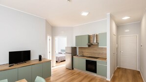 A modern apartment with a kitchen, dining area, and a bedroom. - Street View Apartment (Margherita di Savoia)