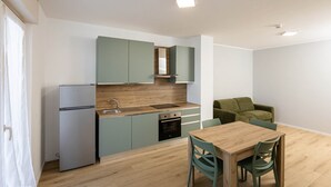 Una cucina moderna con mobili verde chiaro, un piano di lavoro in legno, forno integrato e un'area pranzo con tavolo e sedie in legno.