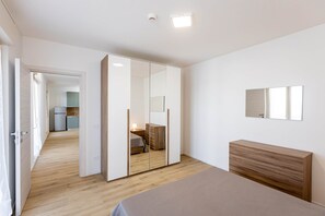 Une chambre à coucher moderne avec un lit en bois, une armoire avec un miroir et une table de chevet.