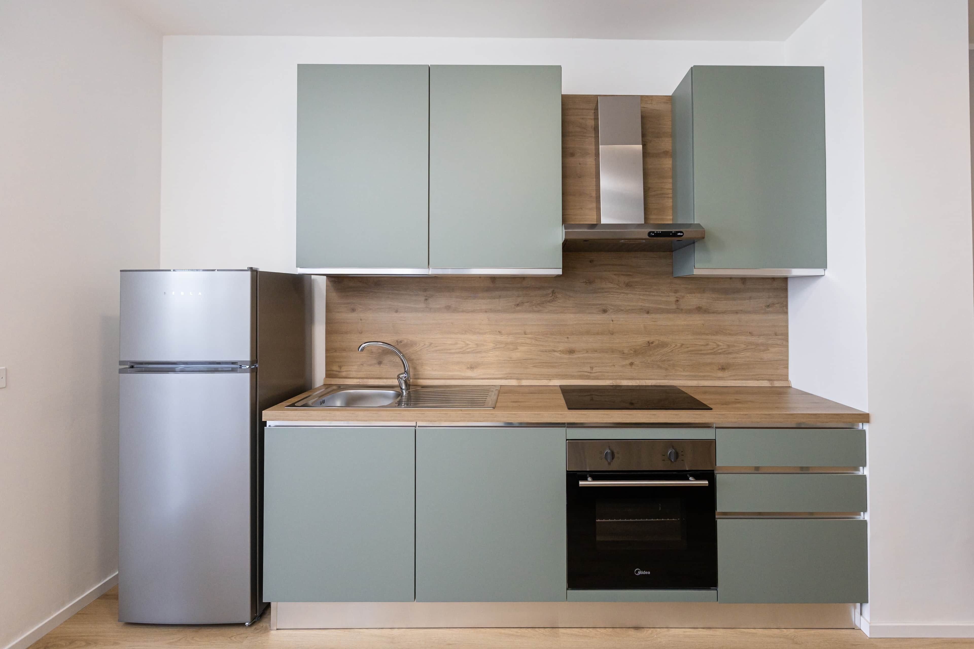 A compact kitchen with a built-in refrigerator, a sink, a stove, and a dishwasher.