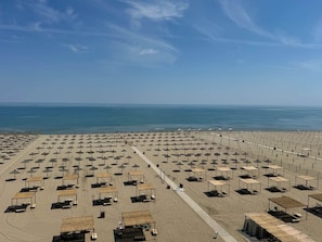 A beach with rows of umbrellas and sun loungers, a clear sky, and the ocean in the background. - Suite with a View of the Sea (Margherita di Savoia)