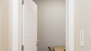 Een smalle gang met houten vloer die leidt naar een kamer met een tafel en stoelen.