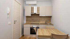 Een compacte keuken met een inbouwoven, een spoelbak en een houten tafel met stoelen.