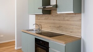 Une cuisine moderne avec des meubles de couleur vert clair, un plan de travail en bois et un lave-vaisselle encastré.