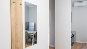 A hallway with a wooden bench, a mirror, and a door leading to a kitchen area. - Sea View Apartment (Margherita di Savoia)