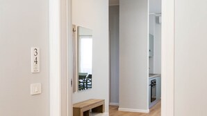 A hallway with a wooden floor, a white wall with a number '34' sign, and a mirror reflecting a dining area. - Sea View Apartment (Margherita di Savoia)
