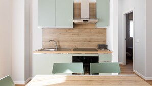 Una cuina moderna amb armaris de color verd clar, taulell de fusta i rentaplats integrat.