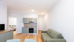 A modern living room with a sofa, a dining table, and a kitchen area with cabinets and a stove. - Sea View Apartment (Margherita di Savoia)