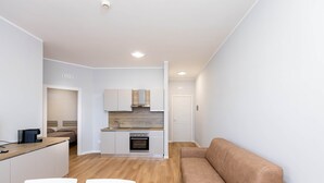 A modern apartment with a kitchenette, a dining area, and a living room with a sofa. - Sea View Apartment (Margherita di Savoia)