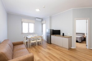 Un espai vital reduït amb una cuineta, zona de dinar, sofà i dormitori.